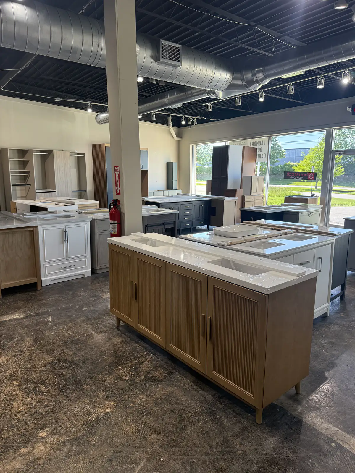 The vanity floor in the Lexington showroom: a fluted wood double vanity in front, white and dark vanities with tops behind it