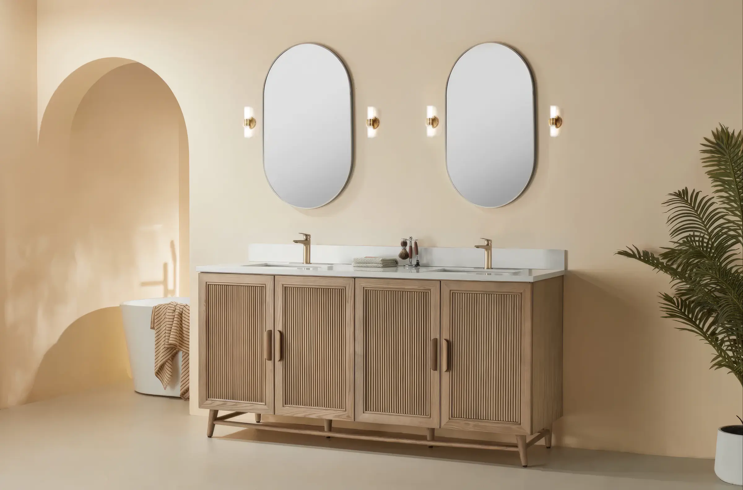 A light oak double vanity with fluted doors under two oval mirrors against a cream wall