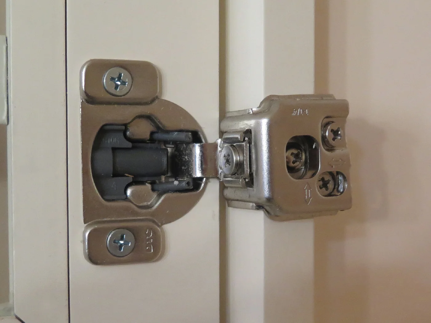 Close view of a soft-close hinge mounted inside a cream cabinet door