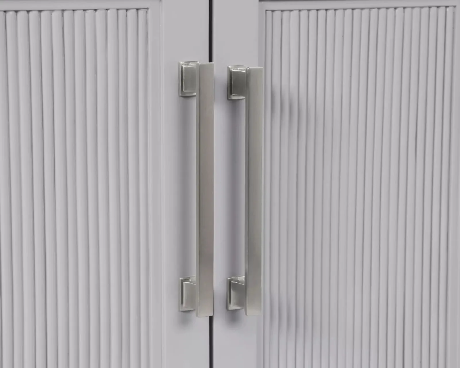 Brushed nickel handles on the vanity fluted light gray doors