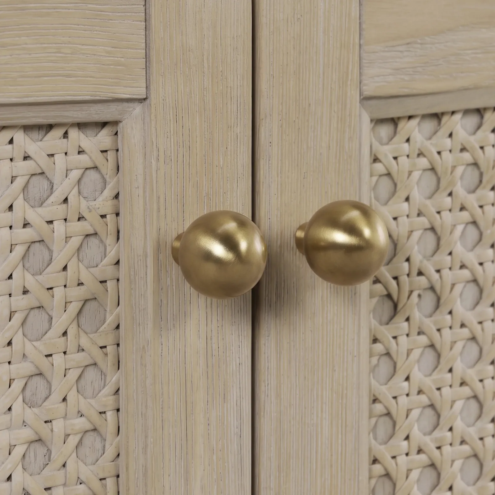 Close-up of the vanity's handwoven cane door panels and gold-finish knobs